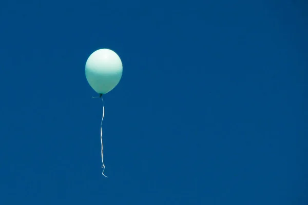 Um único balão azul ciano no céu azul claro . — Fotografia de Stock