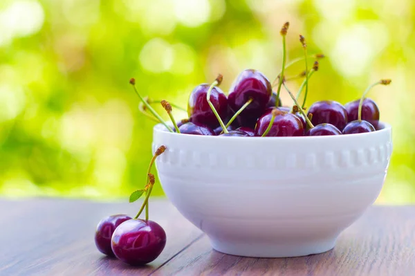Fresh delicious sweet cherries (merry) in a bowl on a wooden table in the sweet cherry garden. Nature, vitamins, vegetarian, organic, healthy, food concept.