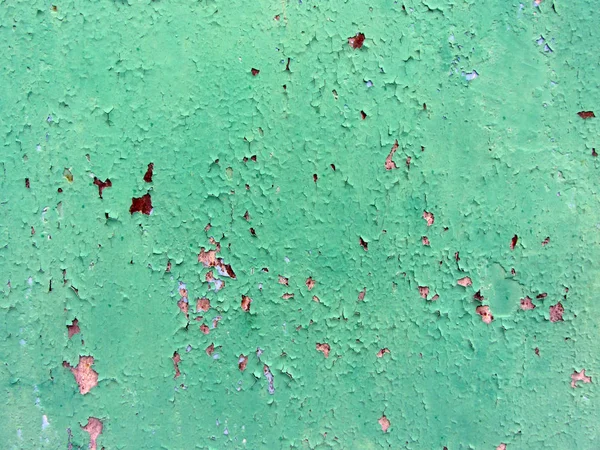 Close-up of green paint peeling old wooden surface, background texture. Wooden background from which the old paint and varnish peeled off, texture. Paint peels off wooden plank.