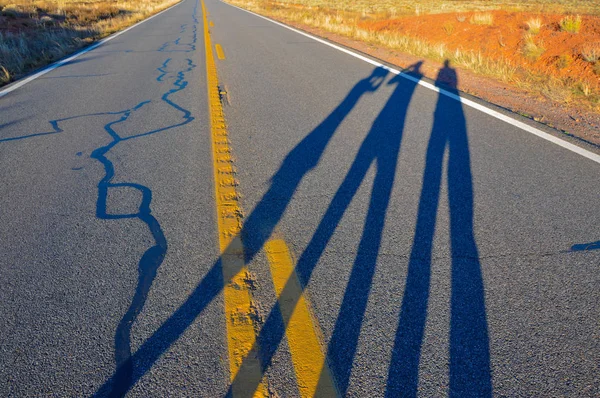 Drei Personen werfen Schatten auf die Straße. — Stockfoto