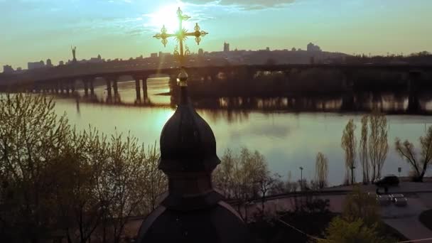 Luftaufnahme einer Holzkirche mit einem großen goldenen Kreuz in der Nähe des breiten Flusses Dnjepr in Kiev — Stockvideo