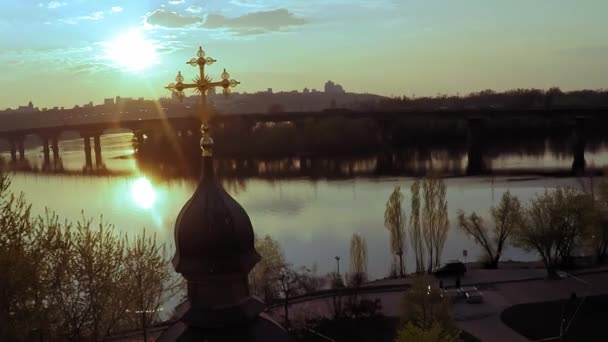 Вид с воздуха на деревянную церковь с большим золотым крестом возле широкой реки Днепр в Киеве — стоковое видео