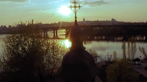 Вид с воздуха на деревянную церковь с большим золотым крестом возле широкой реки Днепр в Киеве — стоковое видео