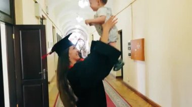 Üniversite koridorunda çocuğuyla birlikte mezun kız