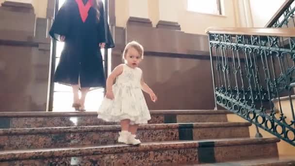 Выпускница с ребенком в университетском коридоре — стоковое видео