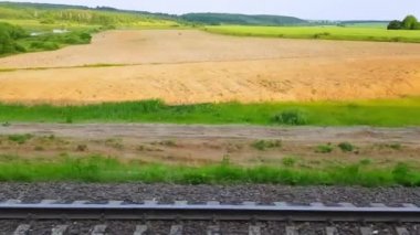 Tepeler ve ormanile güzel bir manzara üzerinde yüksek hızlı tren manzarası. Arabanın penceresinden manzara, otobüs, tren. Güneşli bir günde trenden yolculuk