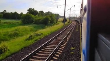 İki mavi yolcu treni buluşmaya gidiyor. Arabanın penceresinden manzara, otobüs, tren. Güneşli bir günde trenden yolculuk