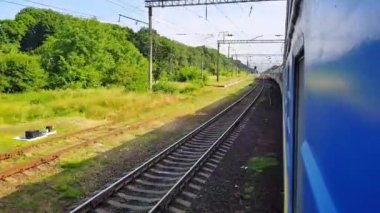 Yolcu treni sola dönüyor. Arabanın penceresinden manzara, otobüs, tren. Güneşli bir günde trenden yolculuk