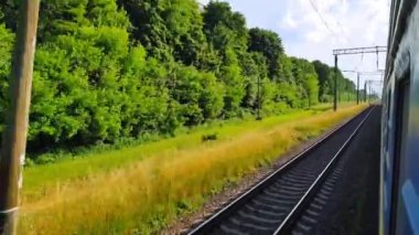 Tepeler ve ormanile güzel bir manzara üzerinde yüksek hızlı tren manzarası. Arabanın penceresinden manzara, otobüs, tren. Güneşli bir günde trenden yolculuk