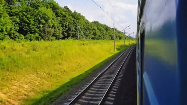 Пасажирський потяг повертається вправо. Вид з вікна на машину, автобус, поїзд. Подорож з поїзда в сонячний день — стокове відео