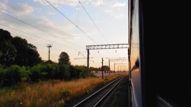 Gün batımından önce tepeler ve orman ile güzel bir manzara üzerinde yüksek hızlı tren manzarası. Arabanın penceresinden manzara, otobüs, tren. Güneşli bir günde trenden yolculuk