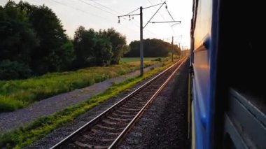 Gün batımından önce tepeler ve orman ile güzel bir manzara üzerinde yüksek hızlı tren manzarası. Arabanın penceresinden manzara, otobüs, tren. Güneşli bir günde trenden yolculuk