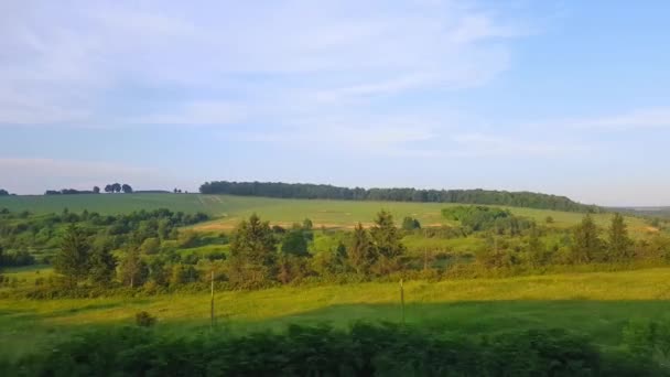 A vista do trem de alta velocidade na bela paisagem com colinas e floresta antes do pôr do sol. A vista da janela do carro, ônibus, trem. Viagem do trem em um dia ensolarado — Vídeo de Stock