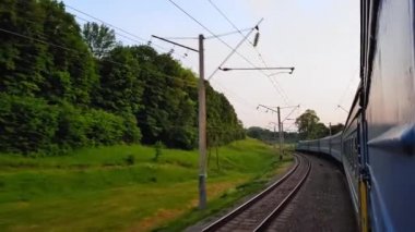 Gün batımından önce tepeler ve orman ile güzel bir manzara üzerinde yüksek hızlı tren manzarası. Arabanın penceresinden manzara, otobüs, tren. Güneşli bir günde trenden yolculuk