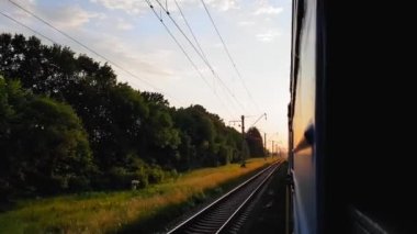 Gün batımından önce tepeler ve orman ile güzel bir manzara üzerinde yüksek hızlı tren manzarası. Arabanın penceresinden manzara, otobüs, tren. Güneşli bir günde trenden yolculuk