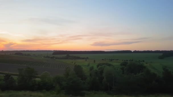 Der Blick aus dem Zug auf die schöne Landschaft mit Hügeln und Wäldern vor Sonnenuntergang. der Blick aus dem Fenster des Autos, Busses, Zuges. Anreise vom Zug. — Stockvideo