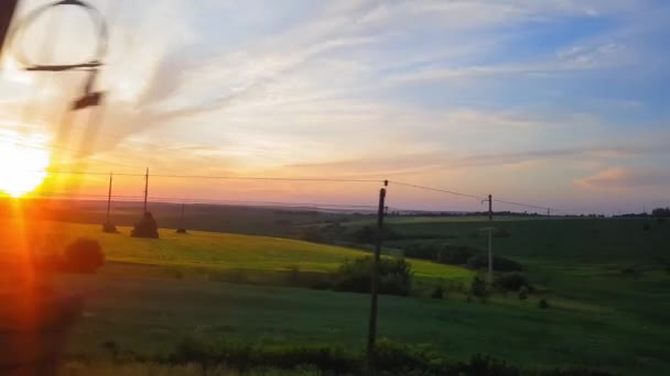 La vista desde el tren en el hermoso paisaje con colinas y bosques antes del atardecer. La vista desde la ventana del coche, autobús, tren. Viaje desde el tren . — Vídeos de Stock