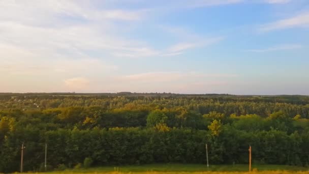 Widok z pociągu na pięknej scenerii z wzgórzami i lasem przed zachodem słońca. Widok z okna samochodu, autobusu, pociągu. Podróż z pociągu. — Wideo stockowe