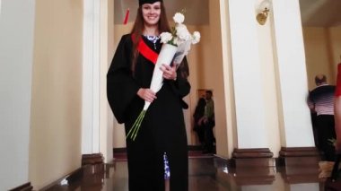 Güzel kız lisansüstü ustası üniversitede çiçeklerle merdivenlerden çıkıyor