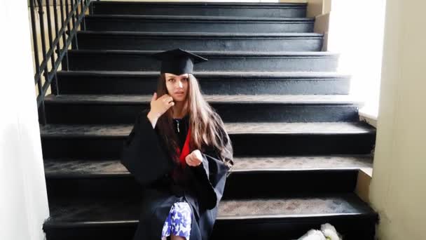 Bela estudante pós-graduação mestre fitas sua perna com um gesso enquanto sentado em degraus de metal na universidade — Vídeo de Stock