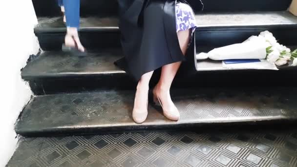Gyönyörű diák posztgraduális mesterszalagok lábát a vakolat, miközben ül a fém lépéseket az egyetemen — Stock videók