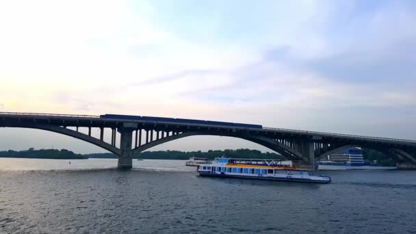 4K, le navire navigue sur le large fleuve du Dniepr avec de grands ponts avant le coucher du soleil — Video