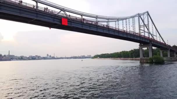 4K. Una barca naviga sotto un ampio ponte attraverso il fiume Dnieper a Kiev — Video Stock