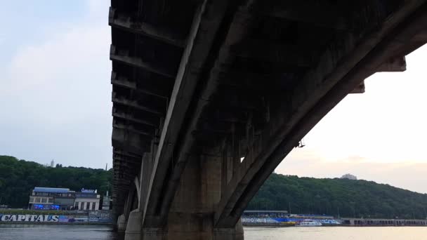 4K. ένα σκάφος πλέει κάτω από μια πλατιά γέφυρα στον Δνείπερο ποταμό στο Κίεβο — Αρχείο Βίντεο