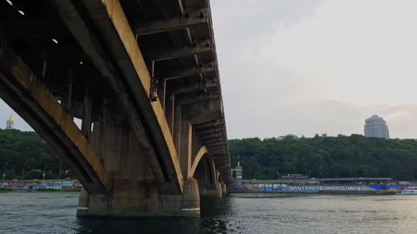 4K. Una barca naviga sotto un ampio ponte attraverso il fiume Dnieper a Kiev — Video Stock