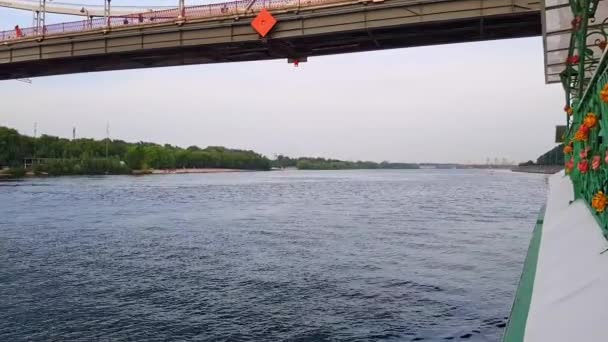 4K. Una barca naviga sotto un ampio ponte attraverso il fiume Dnieper a Kiev — Video Stock