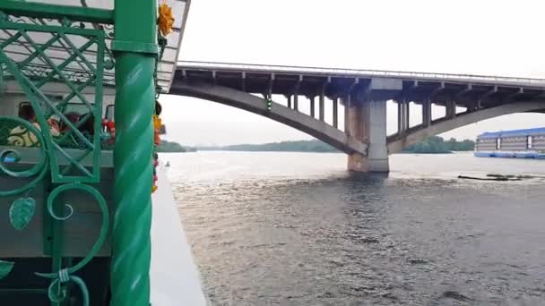 4K. Um barco navega sob uma ponte larga através do rio Dnieper em Kiev — Vídeo de Stock