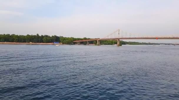 4k fährt das Schiff auf dem breiten Fluss Dnjepr mit großen Brücken vor dem Sonnenuntergang — Stockvideo