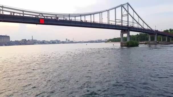 4K. ένα σκάφος πλέει κάτω από μια πλατιά γέφυρα στον Δνείπερο ποταμό στο Κίεβο — Αρχείο Βίντεο