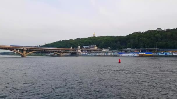 4К, корабль отплывает по широкой реке Днепра с большими мостами перед закатом — стоковое видео