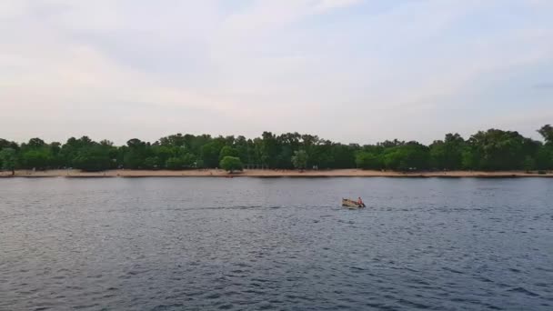 4K, le navire navigue sur le large fleuve du Dniepr avec un pêcheur dans un bateau avant le coucher du soleil — Video