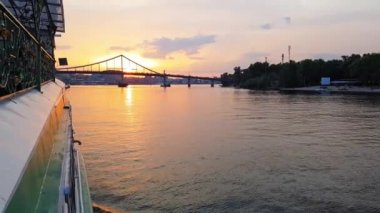 4k. gün batımı öncesinde büyük köprüler ile geniş nehir Dinyeper üzerinde gemi yelken