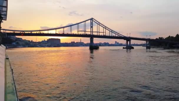 4K. O navio navega no rio Dnieper com grandes pontes antes do pôr-do-sol — Vídeo de Stock