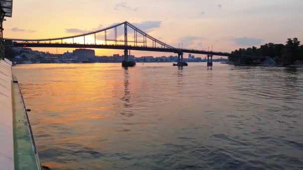 4k. Das Schiff fährt auf dem breiten Fluss Dnjepr mit großen Brücken vor Sonnenuntergang — Stockvideo