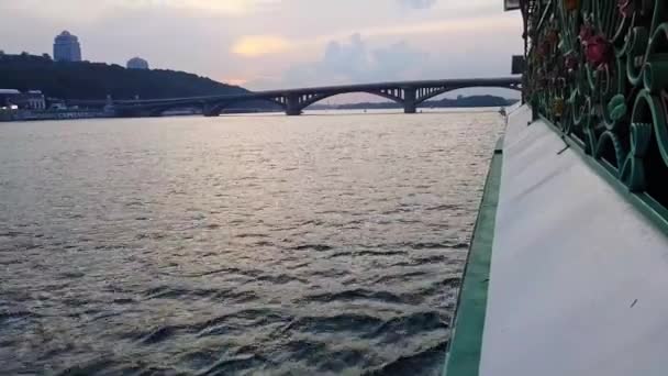 4K. Le navire navigue sur la large rivière Dniepr avec de grands ponts avant le coucher du soleil — Video