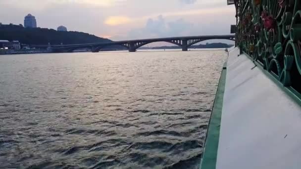 4k. het schip vaart op de brede rivier Dnjepr met grote bruggen voor zonsondergang — Stockvideo