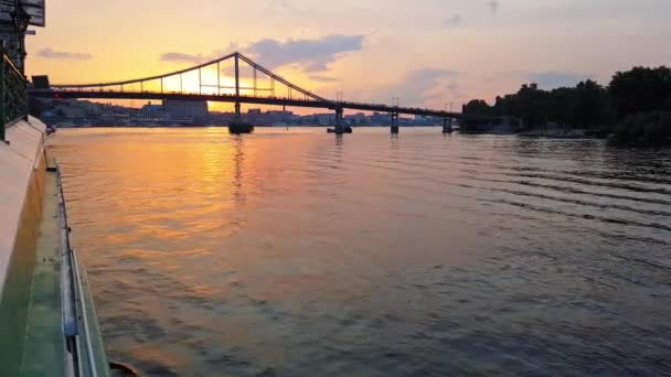 4K. Le navire navigue sur la large rivière Dniepr avec de grands ponts avant le coucher du soleil — Video