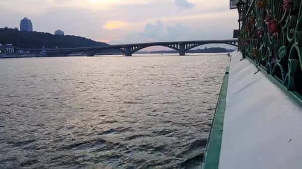 4K. Le navire navigue sur la large rivière Dniepr avec de grands ponts avant le coucher du soleil — Video