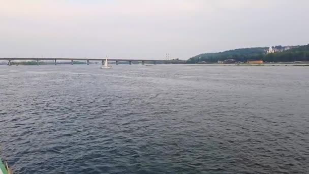 4k. het schip vaart op de brede rivier Dnjepr met grote bruggen voor zonsondergang — Stockvideo