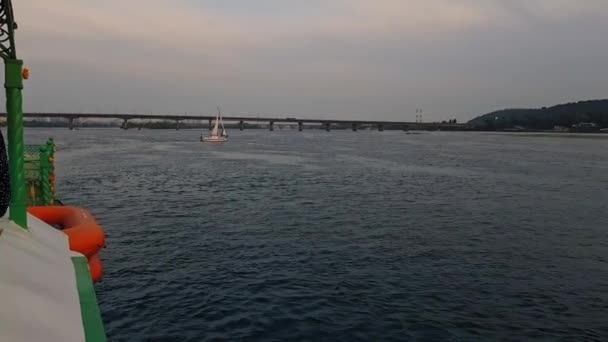 4k. het schip vaart op de brede rivier Dnjepr met grote bruggen voor zonsondergang — Stockvideo