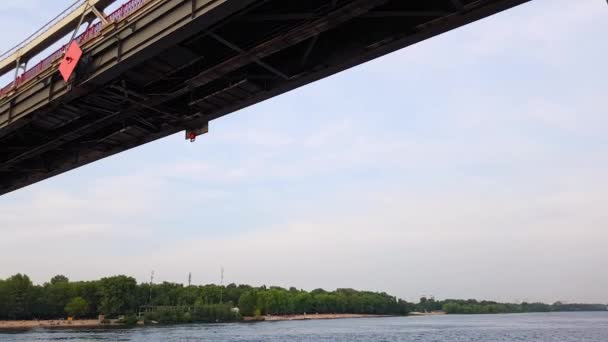 4K. Una barca naviga sotto un ampio ponte attraverso il fiume Dnieper a Kiev — Video Stock