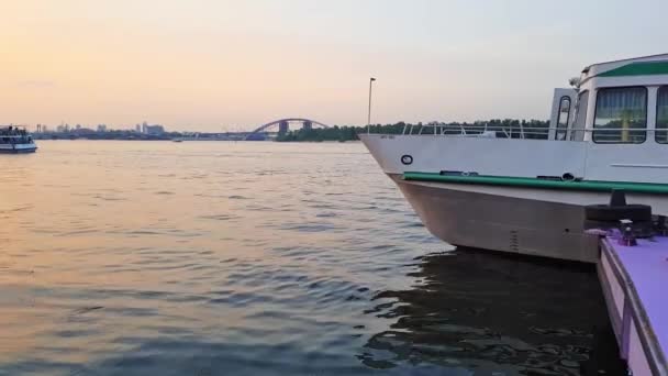 4k. Das Schiff fährt auf dem breiten Fluss Dnjepr mit großen Brücken vor Sonnenuntergang — Stockvideo