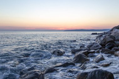 Deniz dalgası, Holy Mount Athos sahilinin yakınında gün batımında taşlar vurur