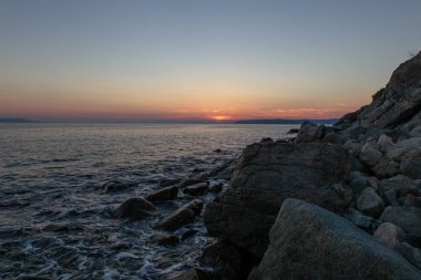 Deniz dalgası, Holy Mount Athos sahilinin yakınında gün batımında taşlar vurur