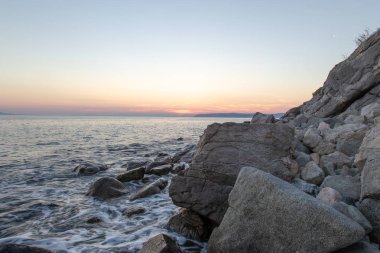 Deniz dalgası, Holy Mount Athos sahilinin yakınında gün batımında taşlar vurur