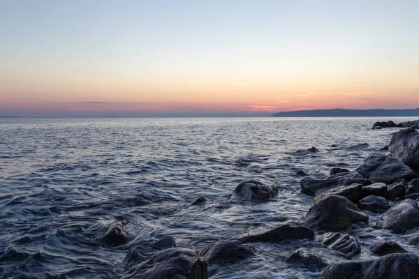 Deniz dalgası, Holy Mount Athos sahilinin yakınında gün batımında taşlar vurur